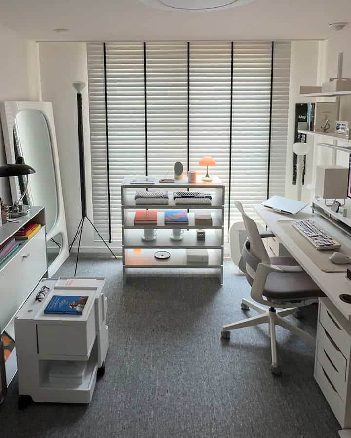 White-toned study and home office space featuring a white desk and chair, shelves, and blinds with a clean, minimal design