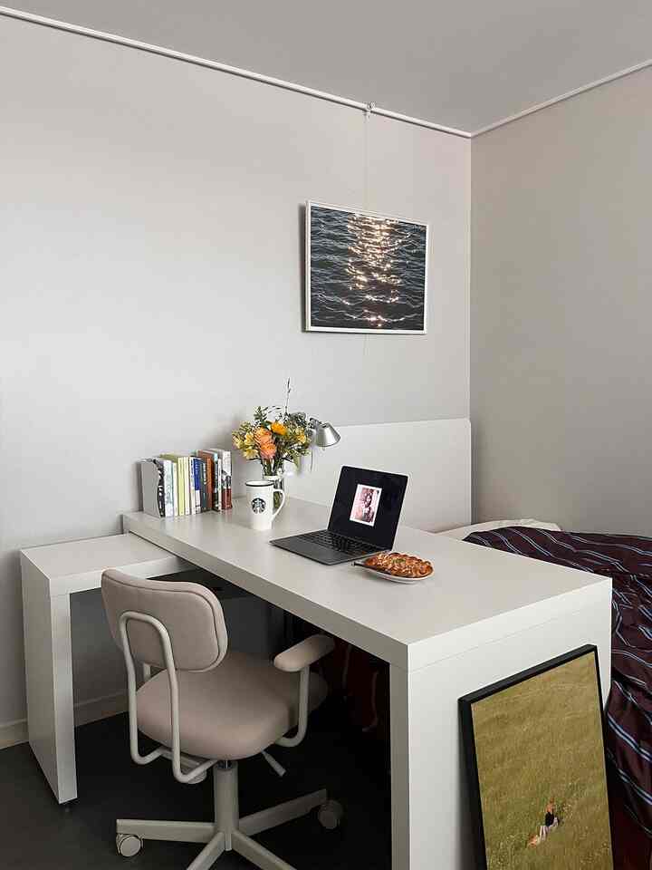 White tone studio bedroom featuring a white desk and chair alongside a bed in a neat home office setting