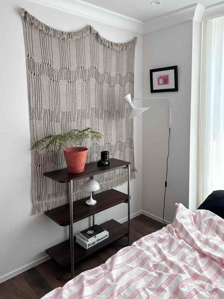 A cozy bedroom featuring white and brown tones, Mid-Century Modern style shelf with plants