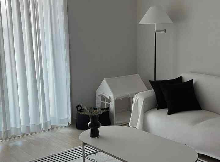 白と黒のモダンなリビング、ソファとフロアランプ、ペットハウスが配置されたシンプルな空間