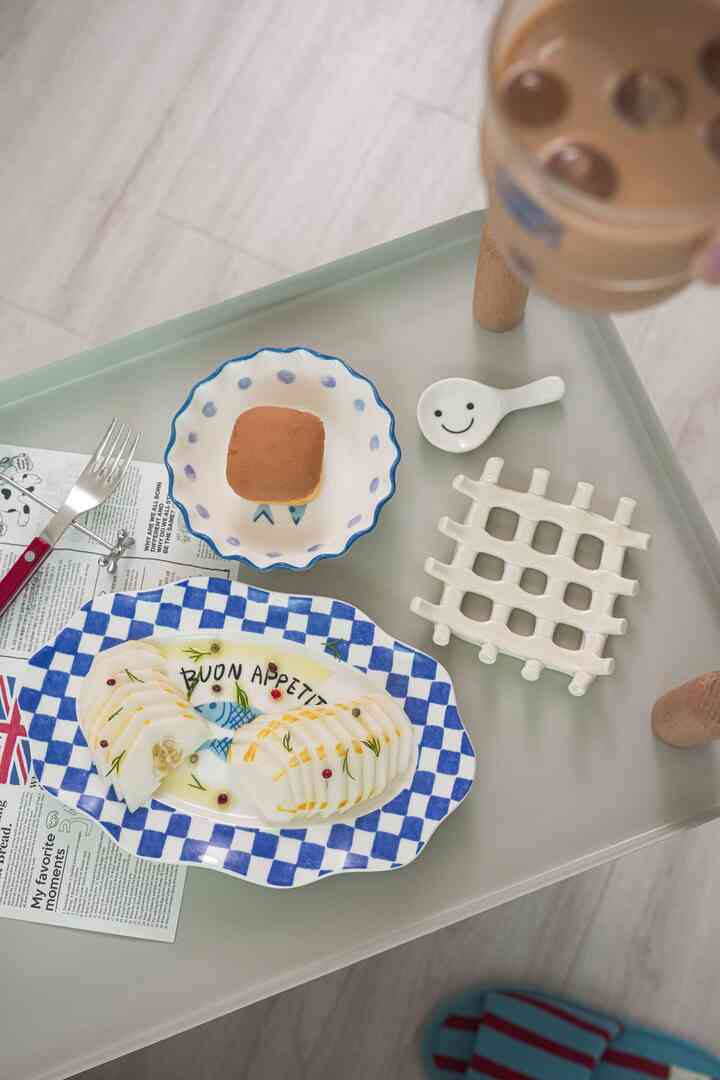 グレーのトレイの上にブルーとホワイトの柄皿、コースター、カトラリーが配置された雰囲気のあるおうちカフェスペース