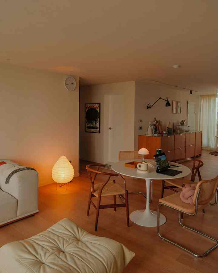 ウッドトーンとホワイトが調和するミッドセンチュリーモダンなリビング・ダイニング、照明と椅子が置かれた温かみのある空間