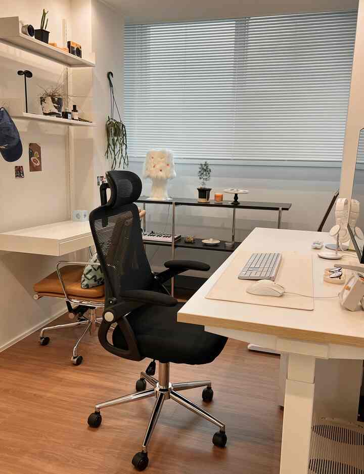 白と茶色のトーンでまとめられたコンパクトなホームオフィス、ミッドセンチュリーモダンスタイルのオフィスチェアとすっきりとしたデスクが配置された雰囲気あるインテリア