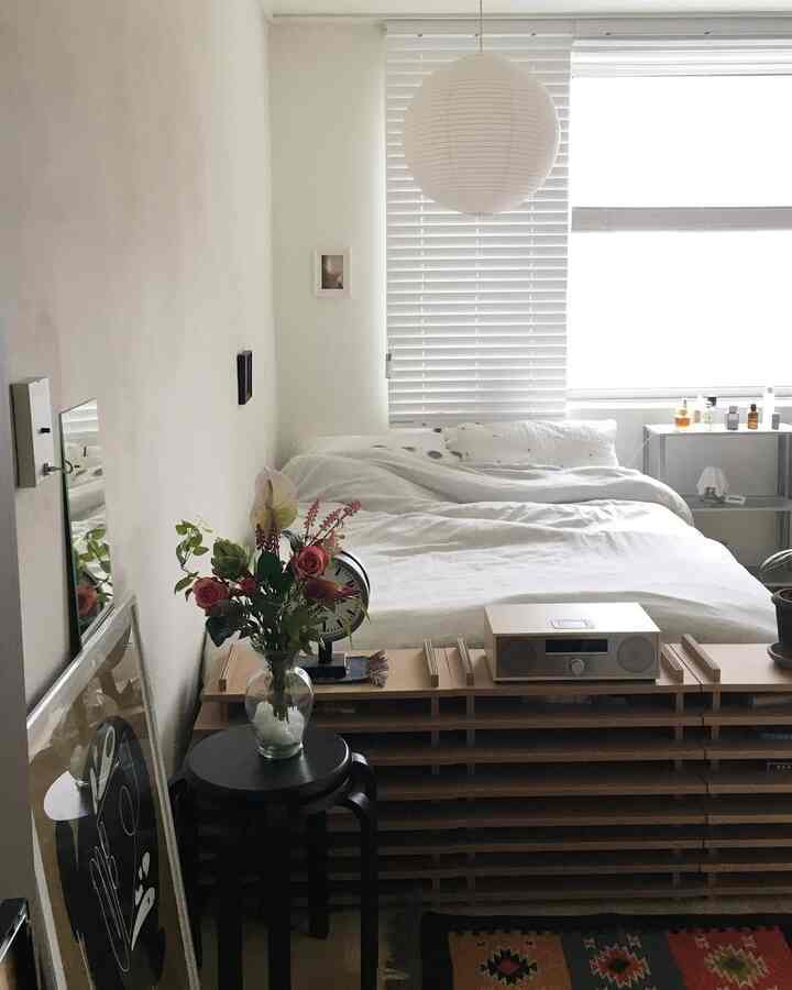 ホワイトとライトグレーの色調のワンルーム寝室、シンプルな家具と寝具が配置された雰囲気のあるインテリア