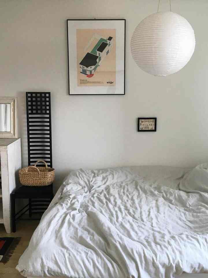 ライトグレーとナチュラルな色調のワンルーム寝室、白いペンダントライトとシンプルな家具が配置された落ち着いた空間