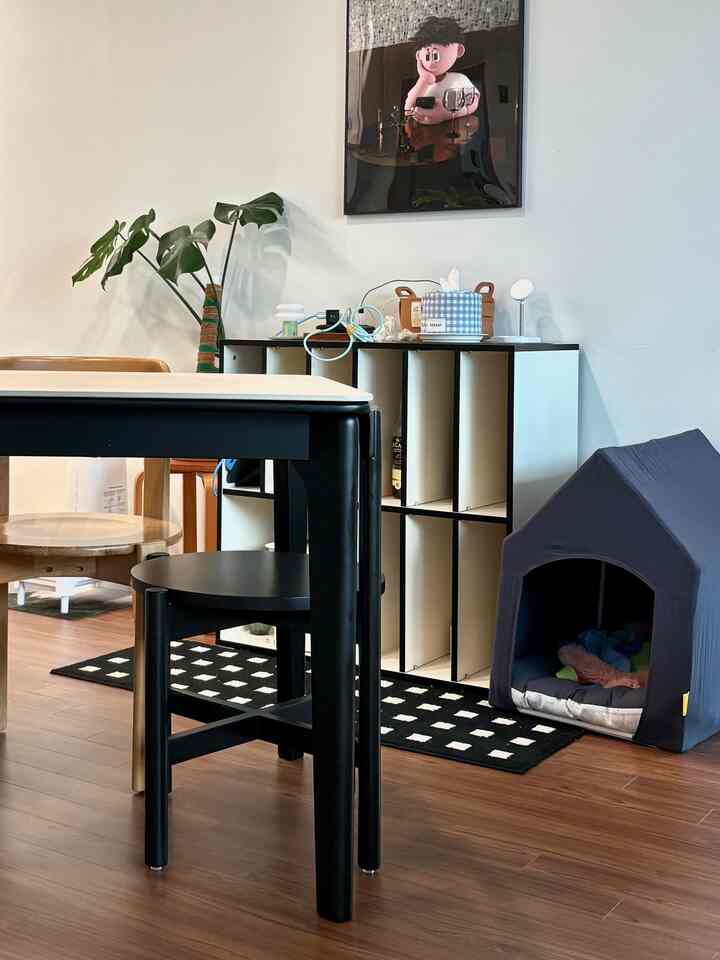 ブラックとウッドトーンが調和したリビングのダイニングスペース、ペットハウスと収納キャビネットが配置された落ち着いたインテリア