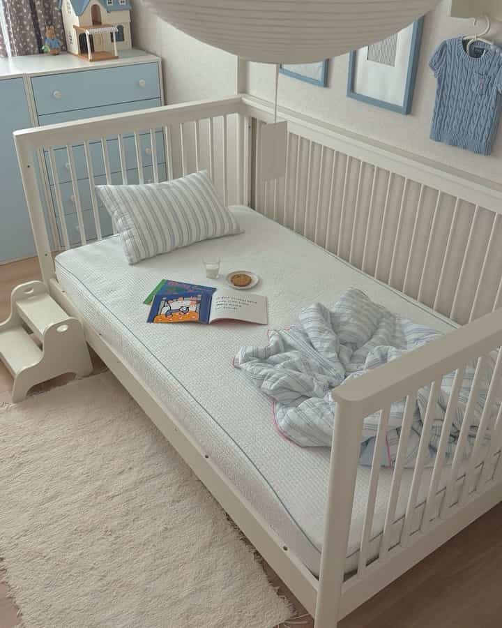 ホワイトとパステルブルーの色調の子供部屋、ベビーベッドと子供用家具が配置されたシンプルで自然な雰囲気のインテリア