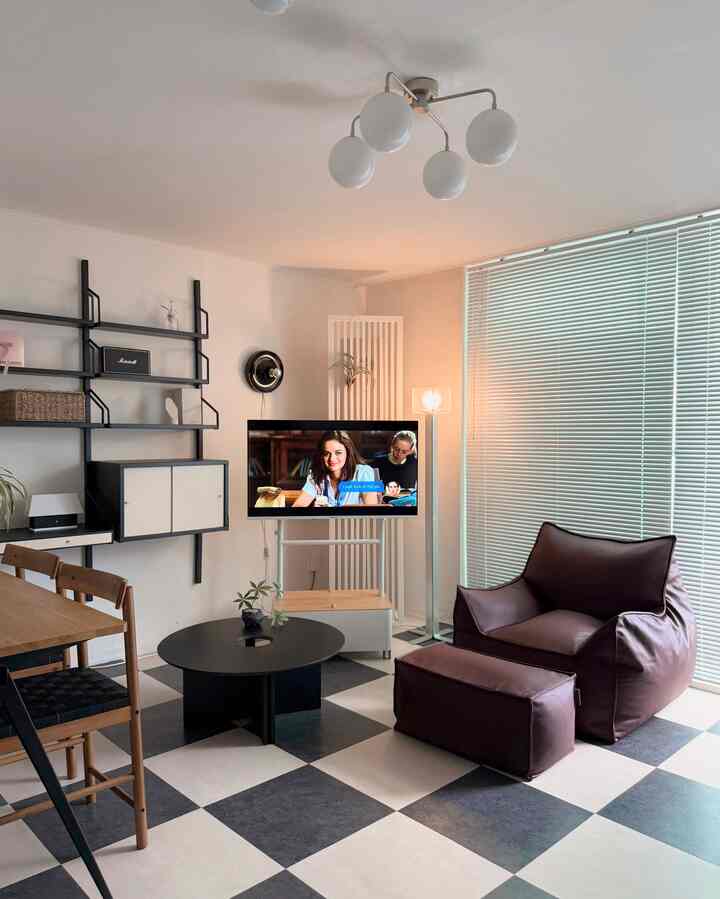 白と黒のチェック柄の床が印象的なリビング、ビーンバッグソファと丸いコーヒーテーブルが配置されたモダンな空間