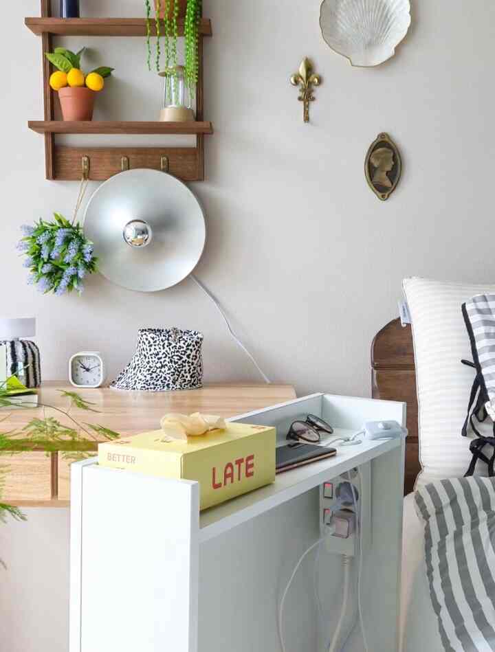 Natural white and wood-toned bedroom featuring gap storage cabinet and decorative wall shelves with cozy ambiance