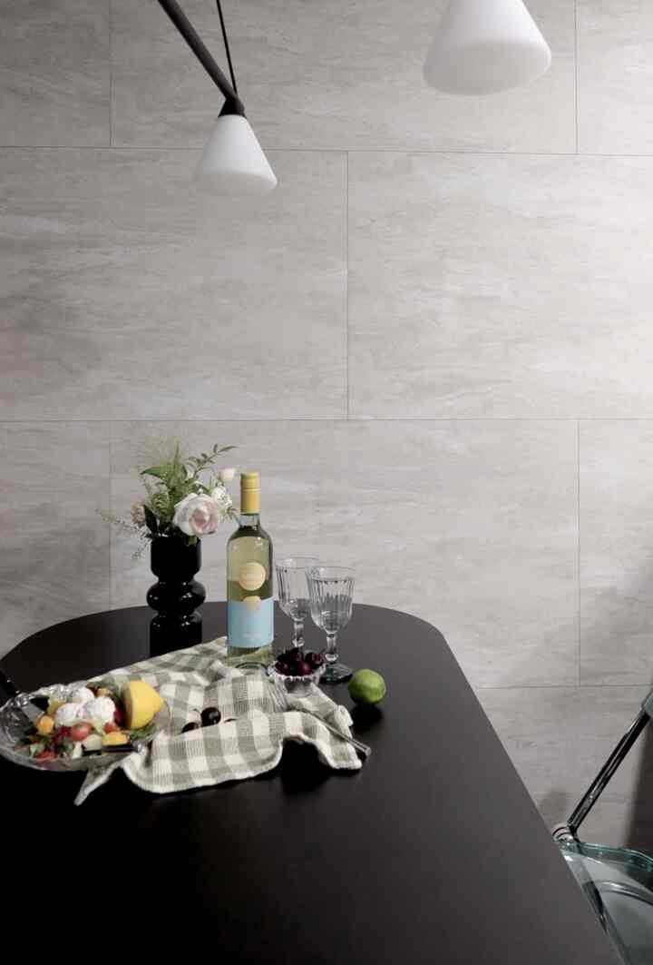 チャコール色の壁と黒い楕円形のダイニングテーブルがあるモダンなダイニング、ワイングラスとオブジェが配置された雰囲気のあるインテリア