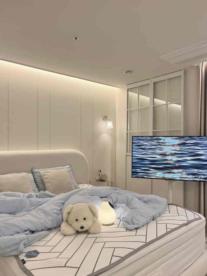 白と青のトーンの寝室、モダンなベッドと冷感寝具、テレビ台と間接照明が調和した涼しげな空間