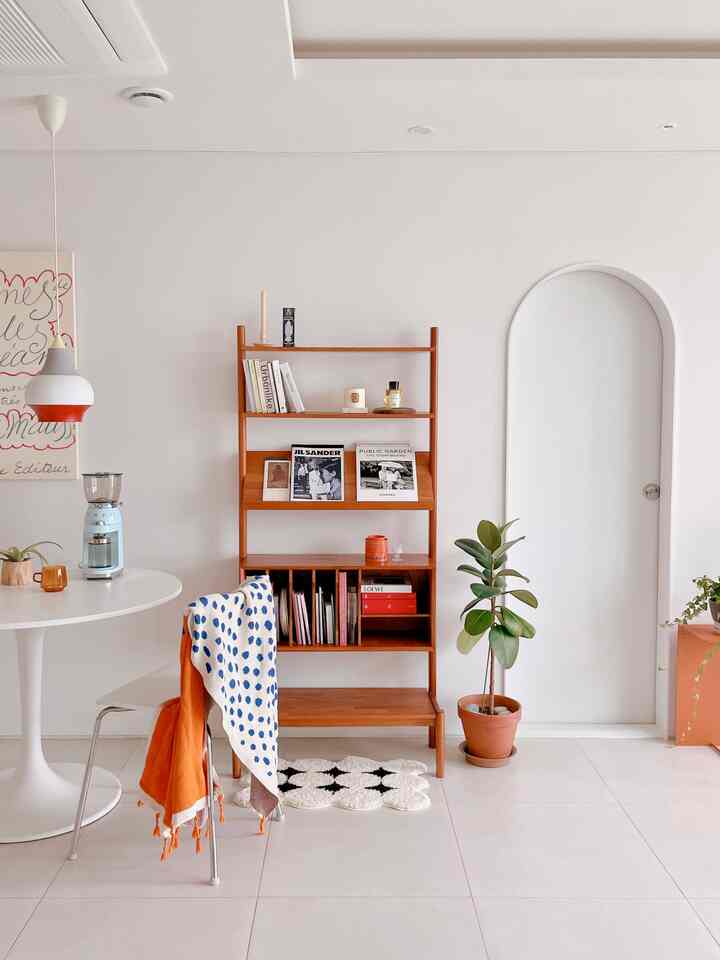 白い壁と木目調の棚、丸い食卓と椅子が配置されたシンプルで植物のあるおうちカフェ空間