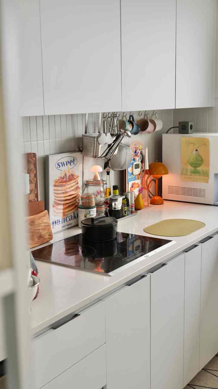 白色調のキッチン、IHコンロとキッチン用具が整然と配置された雰囲気のある空間