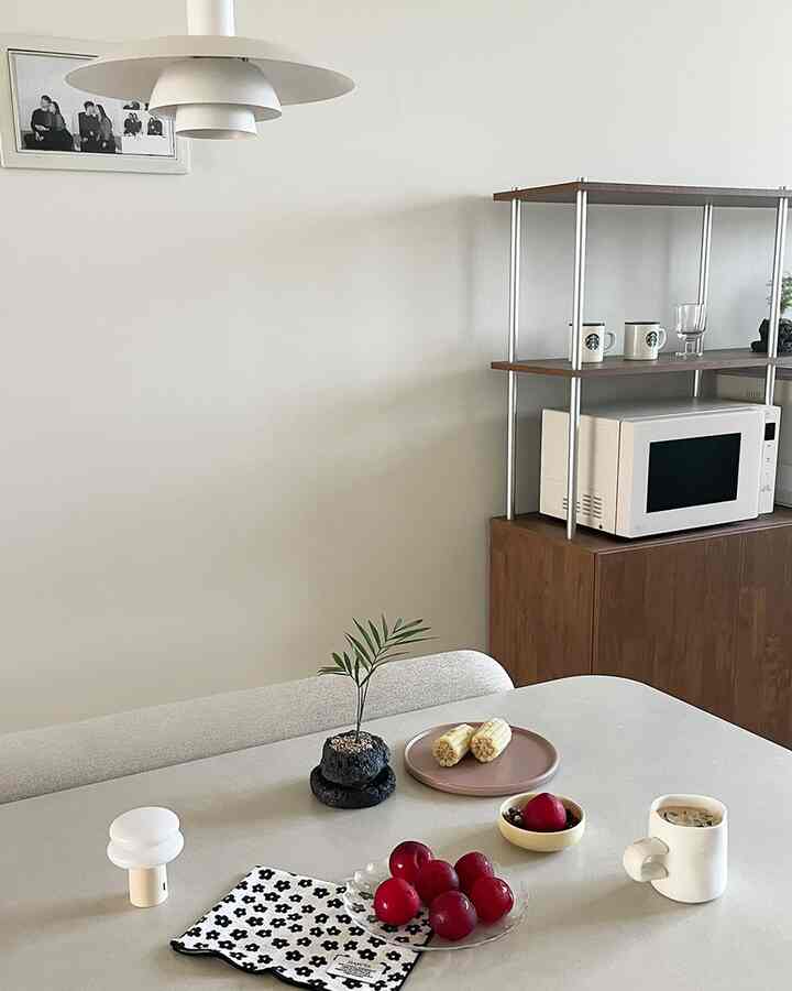 白と木目調が調和したキッチン兼ダイニングスペース、コーヒーと果物が置かれた落ち着いたおうちカフェの雰囲気