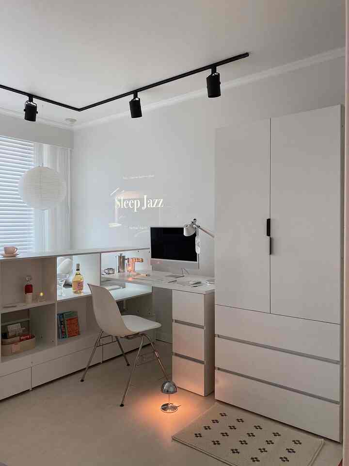 白を基調としたワンルームのホームオフィス、机とチェスト、ワードローブが配置されたシンプルでモダンなインテリア