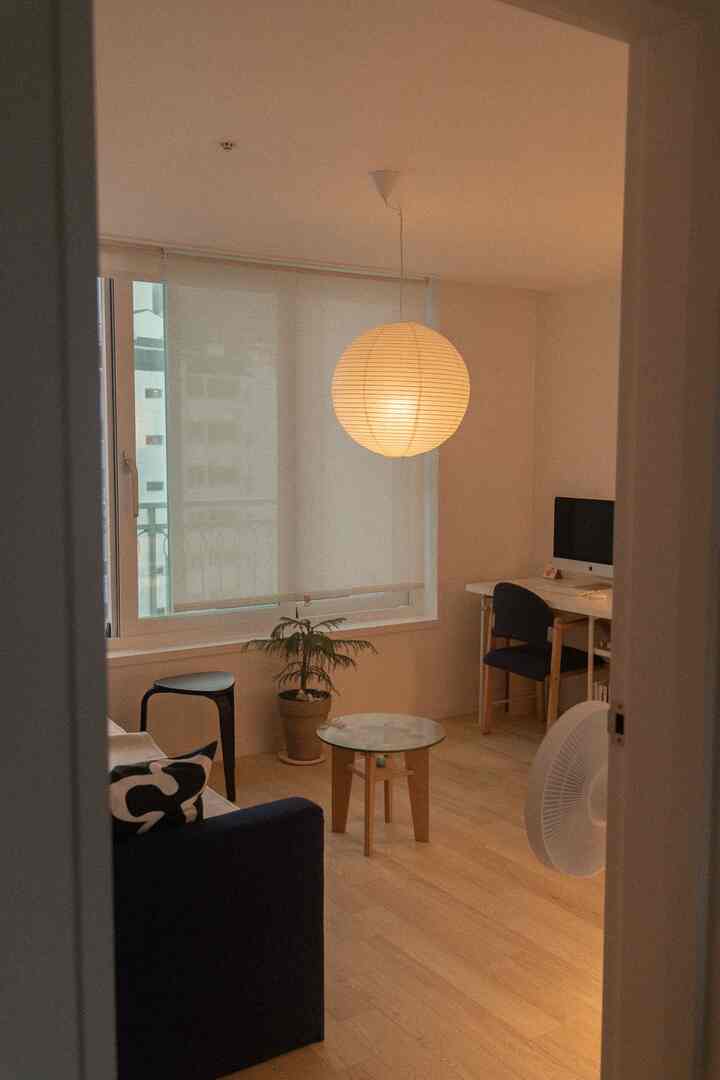 ナチュラルな木目調と白のリビング兼書斎、青いソファとデスクが配置された雰囲気のあるインテリア