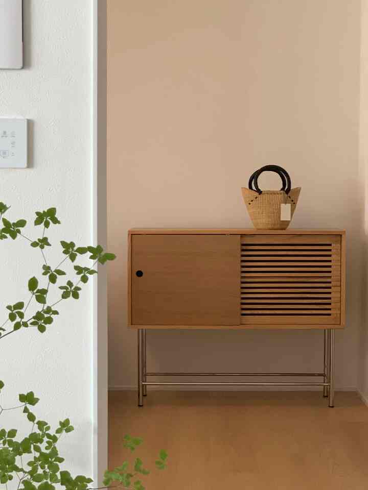 温かみのある木目調と白い壁の玄関、ミニマルな木製キャビネットが配置された印象的な空間