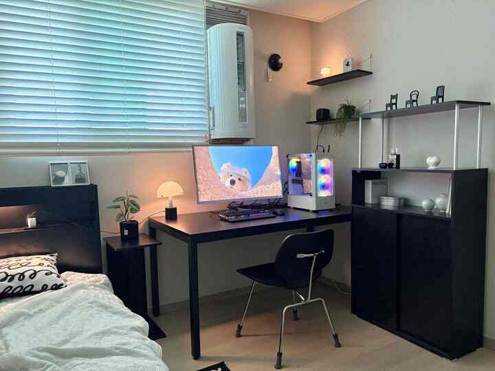 モノトーンの黒家具が中心の二人暮らし用寝室、機能的なデスクとパソコンが配置された清潔で現代的なインテリア