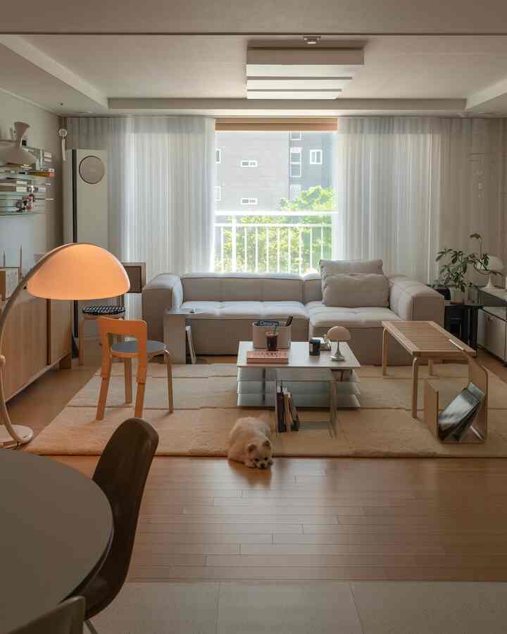 ナチュラルカラーのリビング、モダンなソファと大きなラグ、フロアランプ、ペットと調和のとれた雰囲気のあるインテリア