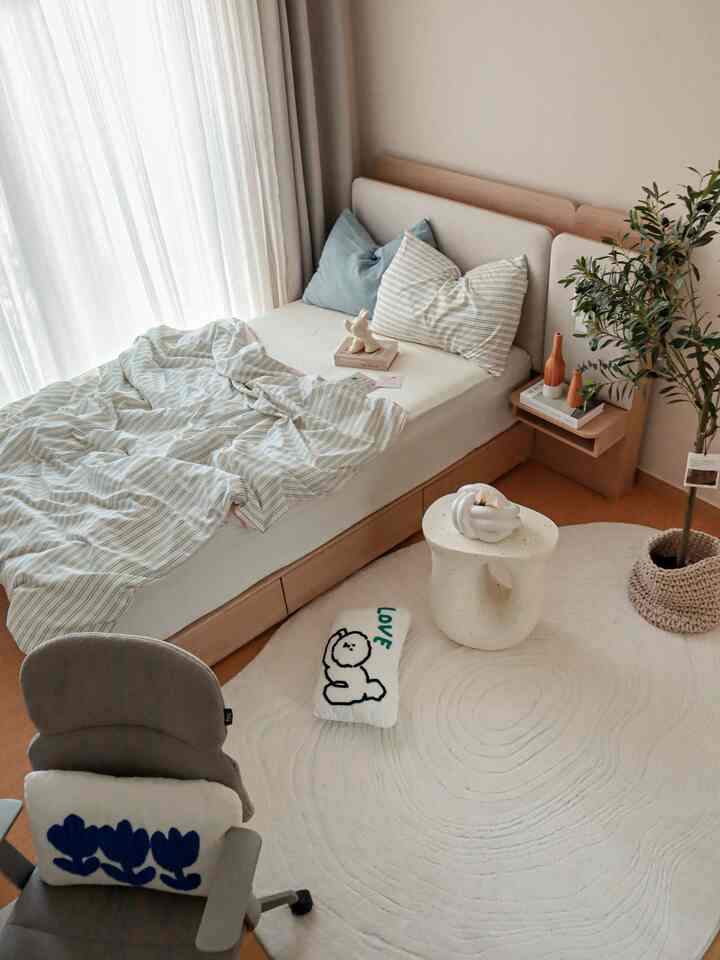 ナチュラルな色調の子供部屋、木製ベッドと白いラグ、シンプルな寝室家具が配置された落ち着いた雰囲気の空間