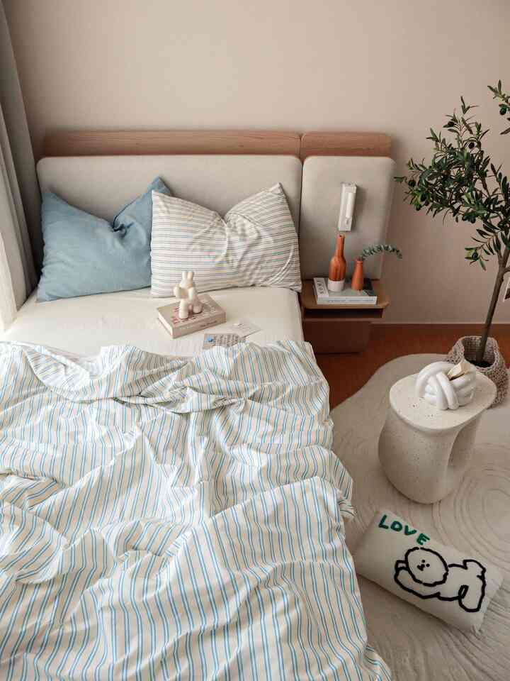 ナチュラルな色調とブルーストライプの寝具が配置された子供部屋、落ち着いた雰囲気のある印象的なインテリア