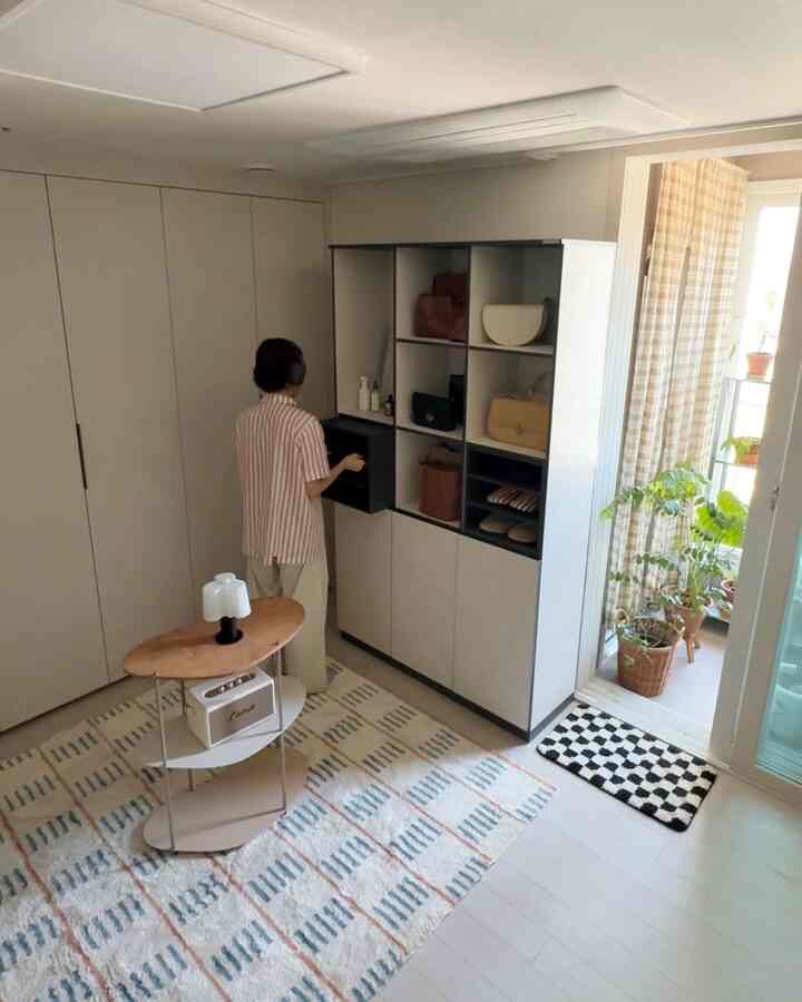 ベージュのウォークインクローゼット、中央に木目調のテーブルと収納キャビネットが配置された清潔感のある空間