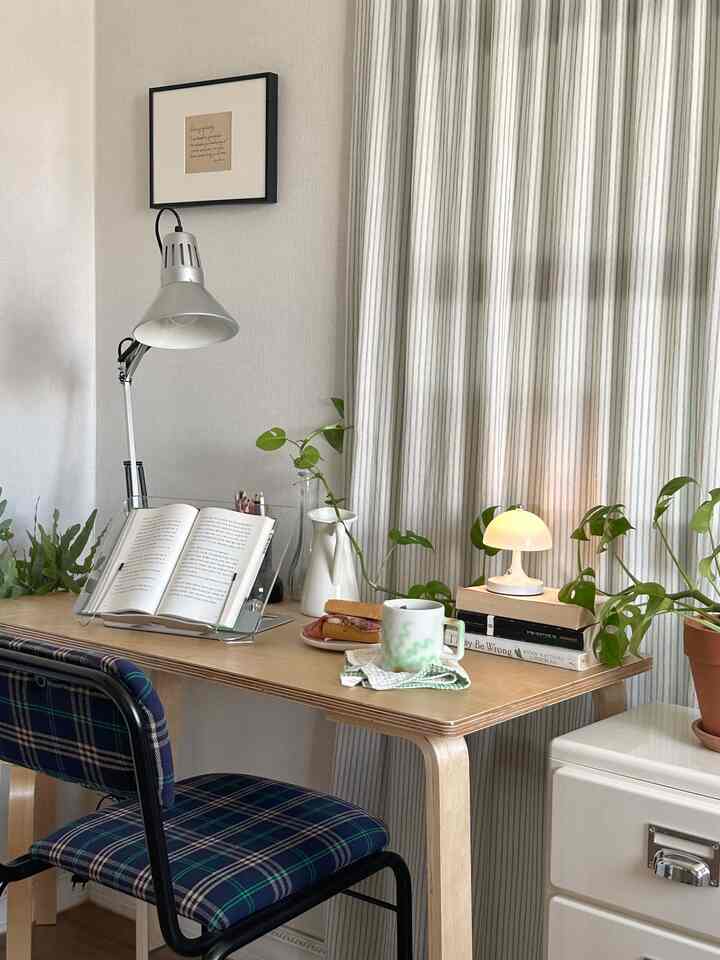 ベージュとウッドトーンのナチュラルなホームオフィス、デスクに照明と植物が配置された雰囲気のある空間