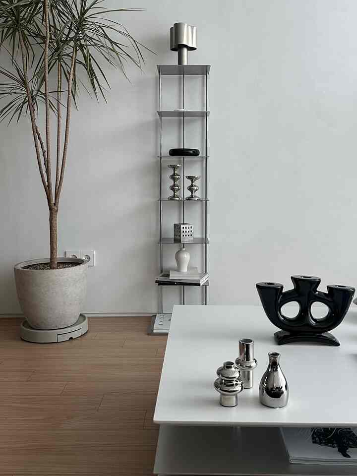 白とシルバー調のリビング、フラットポイントのビブリオシェルフとミニマルなソファテーブルが配置された雰囲気のあるインテリア