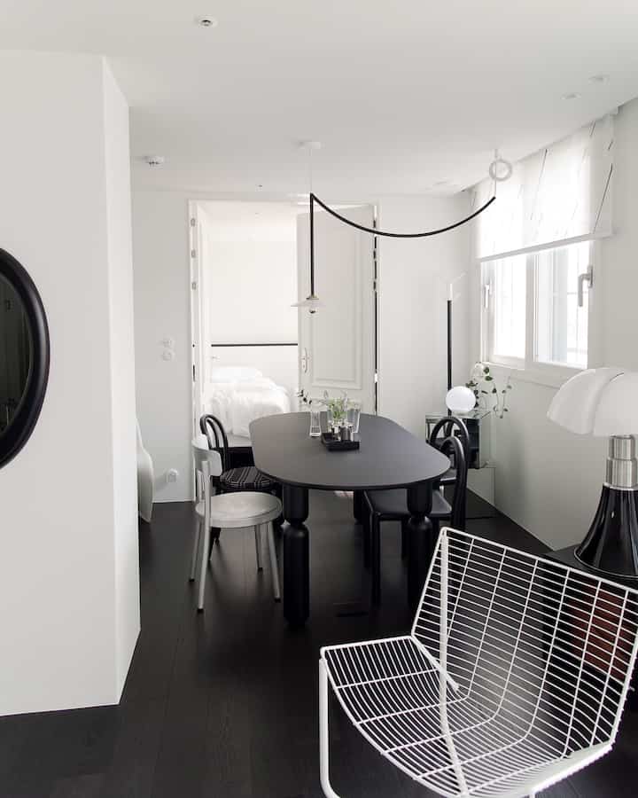 A modern two-person dining room with white walls and ceiling contrasted by black flooring and furniture