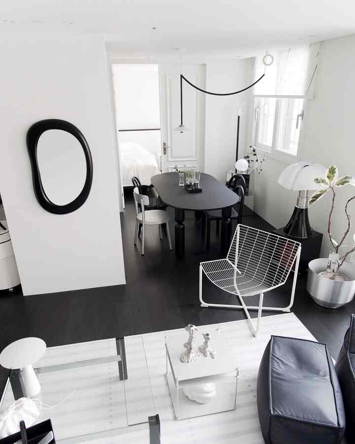 Modern living and dining room with white walls and ceiling, black flooring and furniture creating a sleek atmosphere