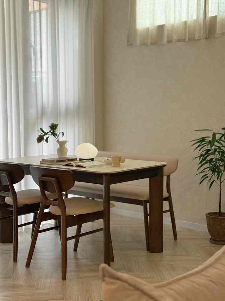 Natural modern dining room in white and brown tones featuring a wood dining table set and linen curtains