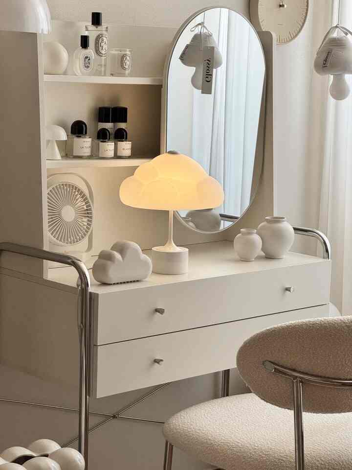 ホワイトとクリーム色調のワンルーム、シンプルなデスクと雲形のテーブルランプが配置されたナチュラルで落ち着いたインテリア