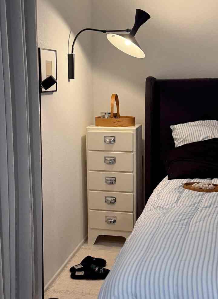 白と黒のトーンの寝室、ナイトスタンドと壁照明が配置された落ち着いた雰囲気のインテリア