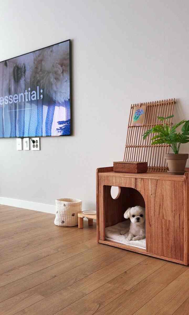 Natural wood tone living room featuring a wooden pet house with a small white dog resting inside, evoking a simple and cozy atmosphere