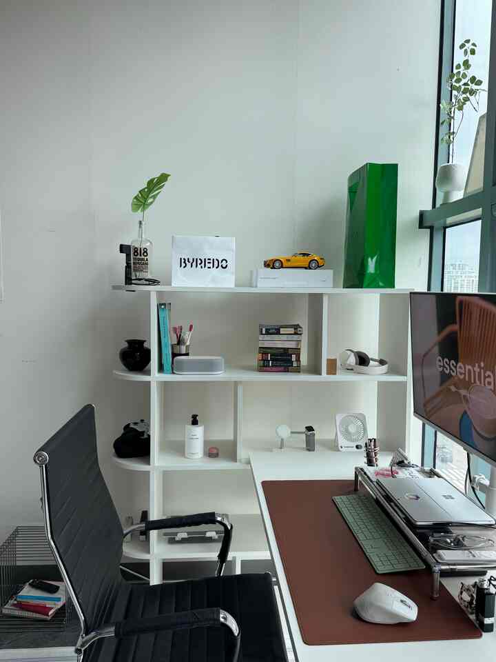 Bright white-toned home office featuring a white bookshelf and desk with a black office chair in a neat workspace