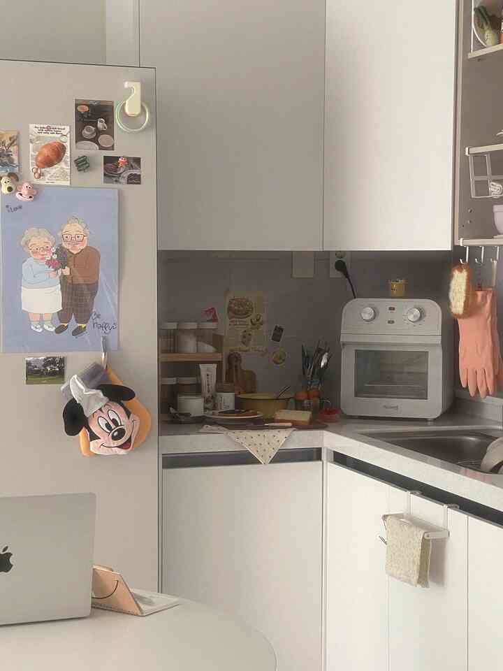 白を基調とした小さなキッチン、丸テーブルとキッチン家電が配置されたミニマルで清潔感のある空間