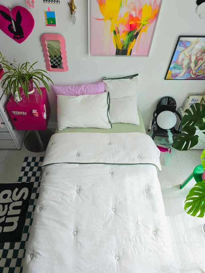 White and pink toned bedroom featuring neat bedding and unique artwork creating a harmonious atmosphere