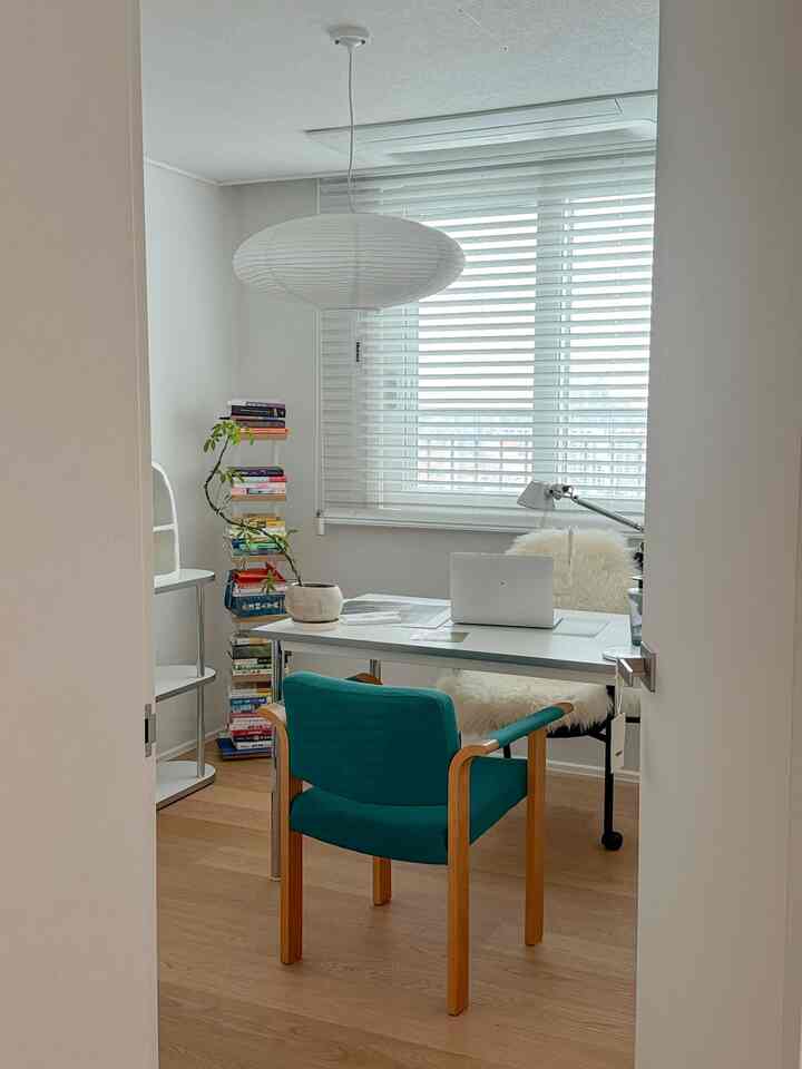 白と木目調の書斎、白いデスクと青いアームチェアが配置されたシンプルで自然な雰囲気のインテリア