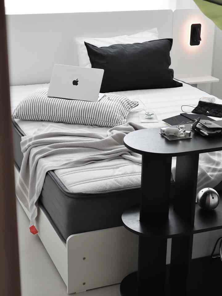 白と黒のトーンの寝室、シンプルなベッドとコーヒーテーブルが配置されたモダンで落ち着いた雰囲気のインテリア