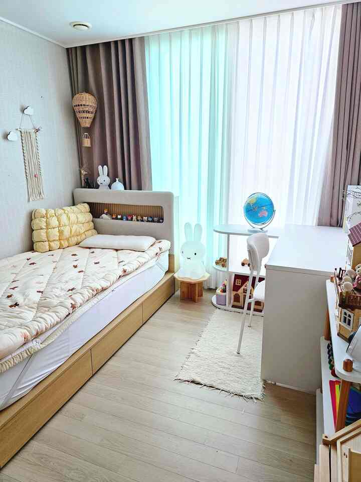 明るいホワイトとベージュの色調の子供部屋、ベッドとデスク、子供のおもちゃが配置された自然な雰囲気のある空間