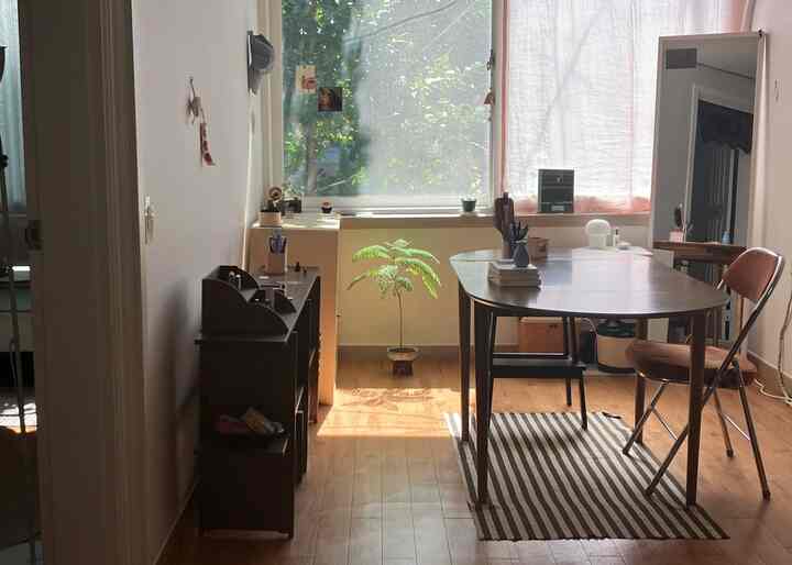 明るい木目調の床とアプリコット色のリネンカーテンがあるダイニングルーム、ストライプのラグと天然木のテーブルが配置された温かみのある空間