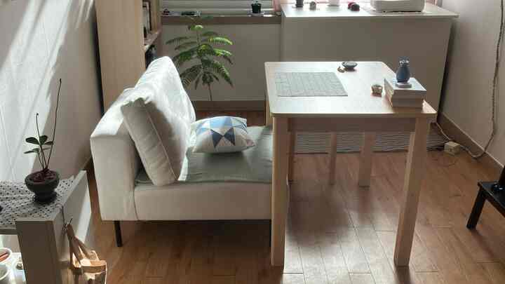 ナチュラルな木目調と白を基調とした狭いリビング、ソファと木製のダイニングテーブルが配置された落ち着いた空間