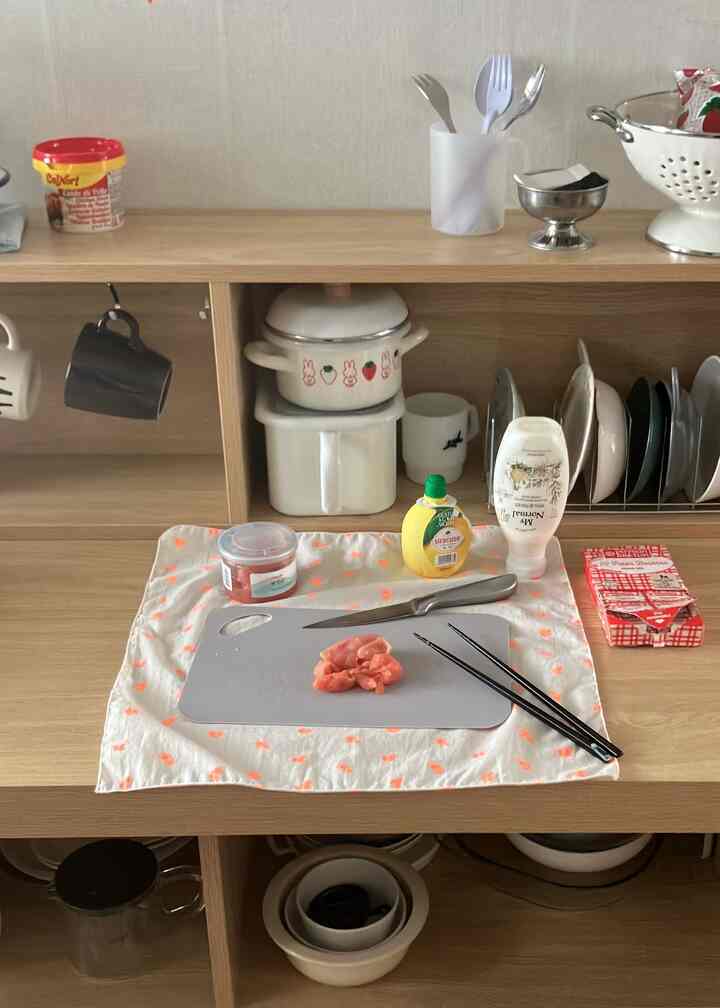 ナチュラルな木目調のキッチン空間、整理された皿とボウルの棚と、まな板の上に包丁と食材が置かれた雰囲気のあるインテリア