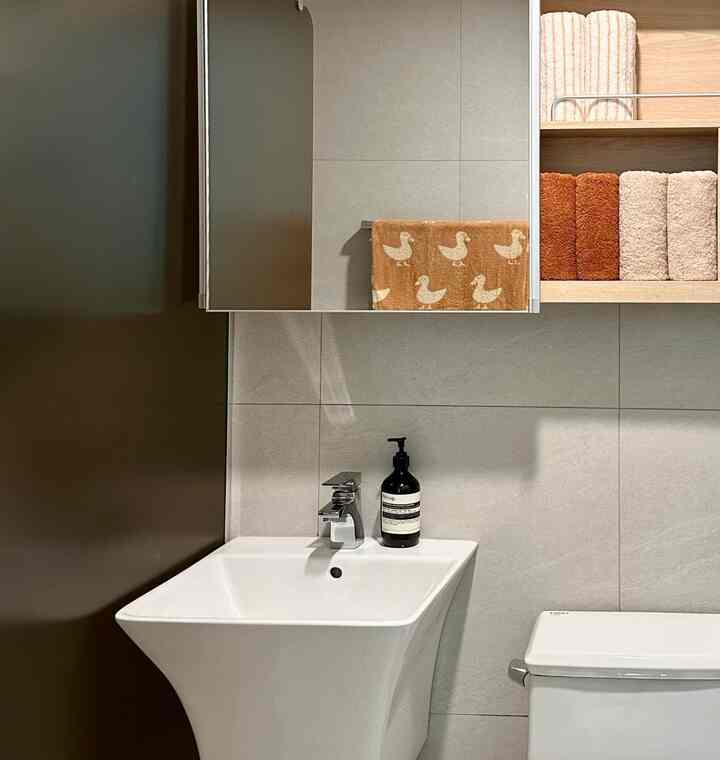 ホワイトとグレーの色調のバスルーム、洗練された洗面台と整然としたタオルが配置されたミニマルで雰囲気のあるインテリア