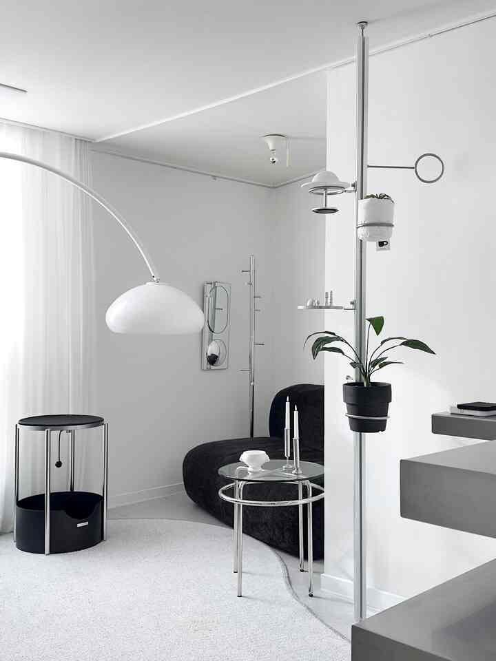 ホワイトとブラックを基調としたモダンなリビング、黒いソファとサイドテーブル、フロアランプと植物が配置された洗練されたインテリア