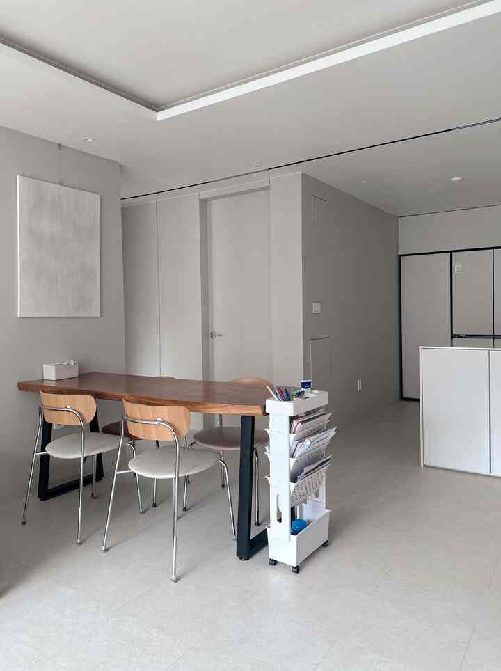 ホワイトとブラウンのキッチン空間、木製のダイニングテーブルとチェア、移動式トロリーが配置されたシンプルなインテリア