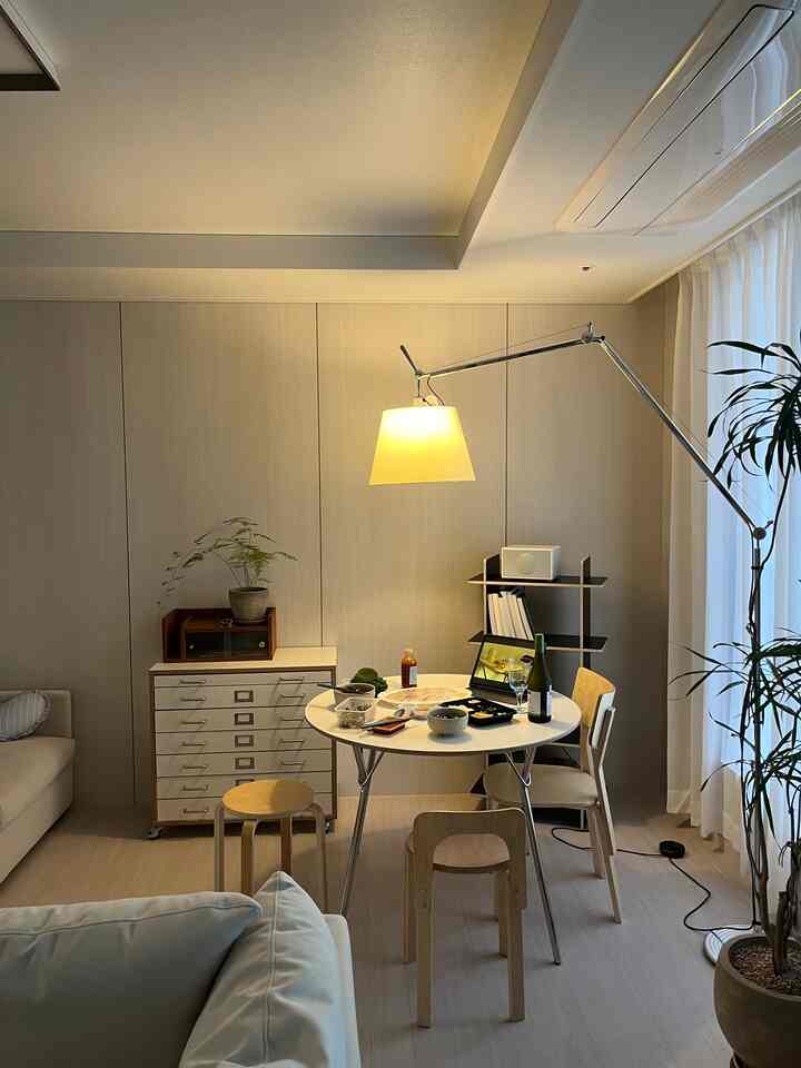 ナチュラルカラーのリビング、円形のダイニングテーブルとスツール、フロアランプが落ち着いた雰囲気を演出するインテリア