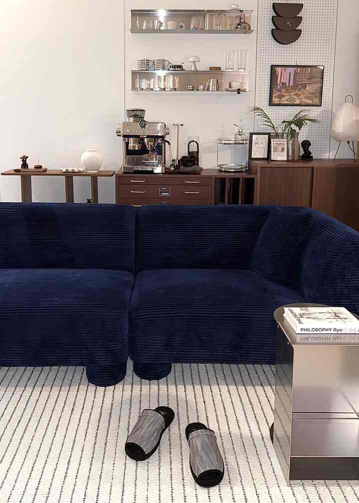 ネイビーのソファと木製家具が配置されたモダンナチュラルな印象のリビングルーム