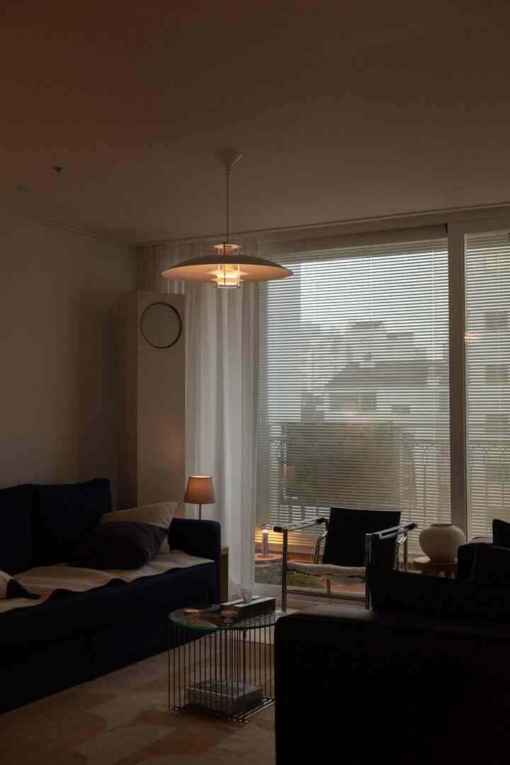 ベージュとネイビーの色調のリビング、ネイビーのソファとブラインドが配置された雰囲気のあるモダンな空間