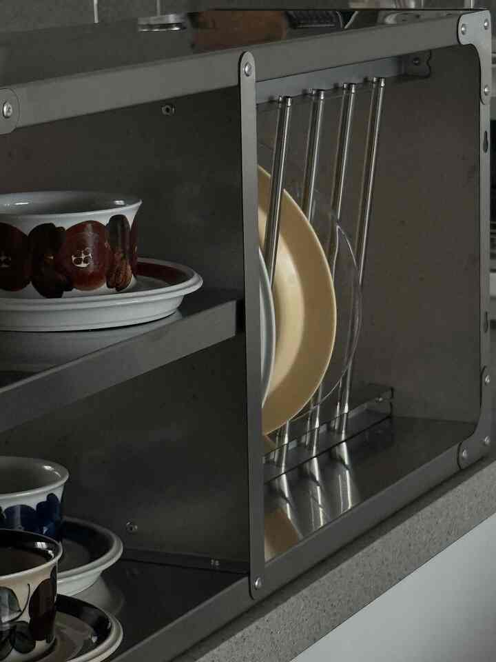 白と茶色のトーンのキッチン棚に、様々な模様の皿やボウルが整然と配置された雰囲気のあるインテリア